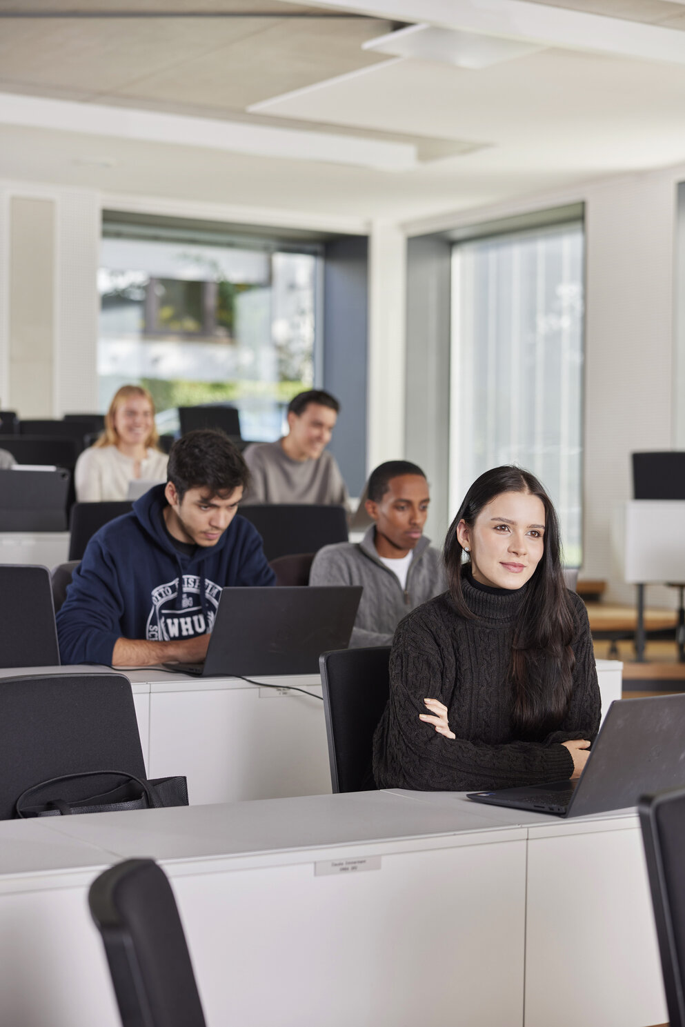 Fünf Studierende des Bachelor of Science-Programms der WHU sitzen in einem Hörsaal auf dem Campus Vallendar