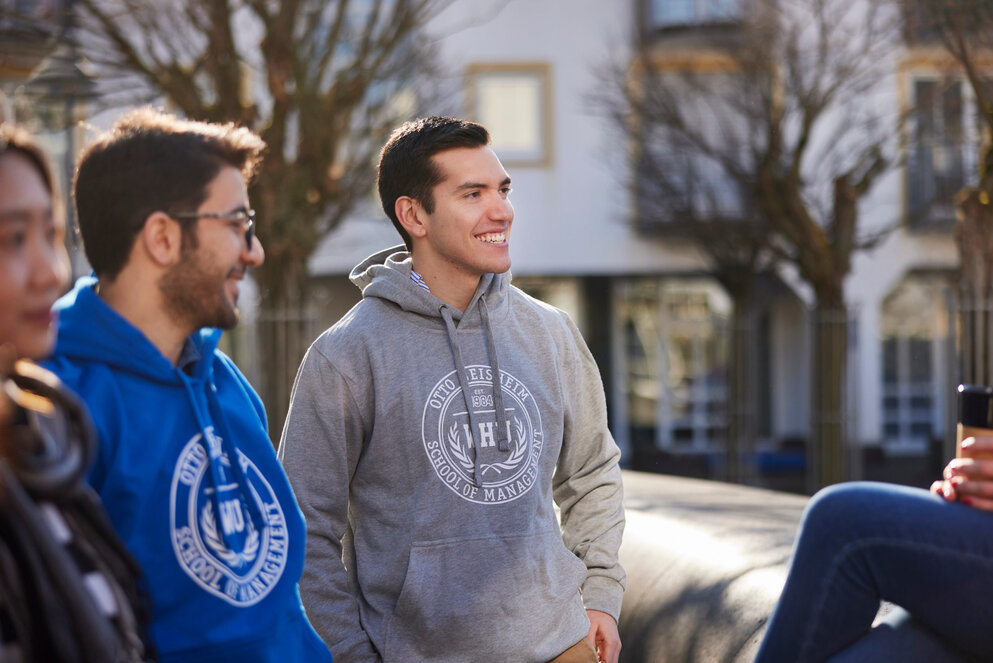 Three young people in hoodies engaged in conversation.