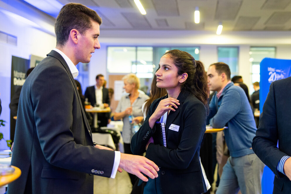 A man and woman discussing at a Two people discussing at a business event.